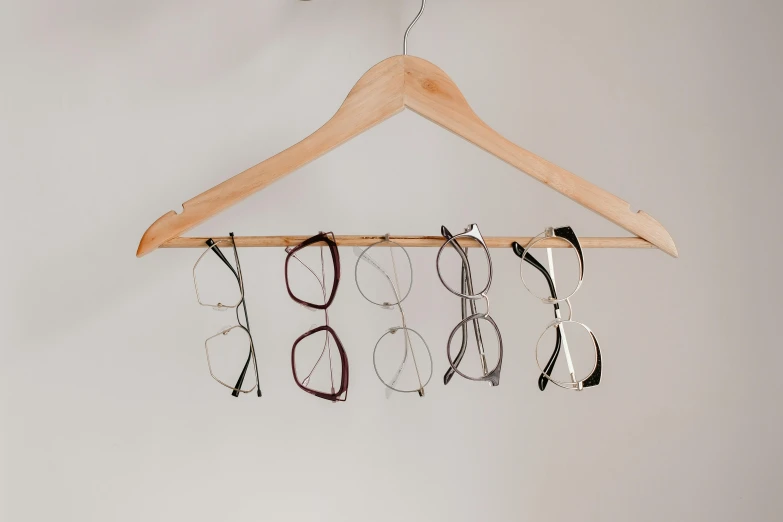 a pair of glasses hanging from a wooden hanger, trending on pexels, various posed, six eyes, designer product, angled