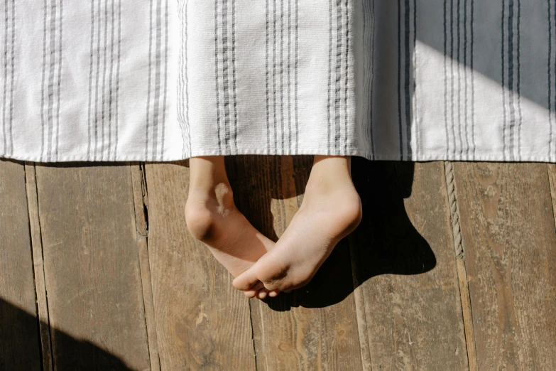a close up of a person's feet on a wooden floor, trending on pexels, happening, wearing a nightgown, white stripes all over its body, cliffside, wearing a towel