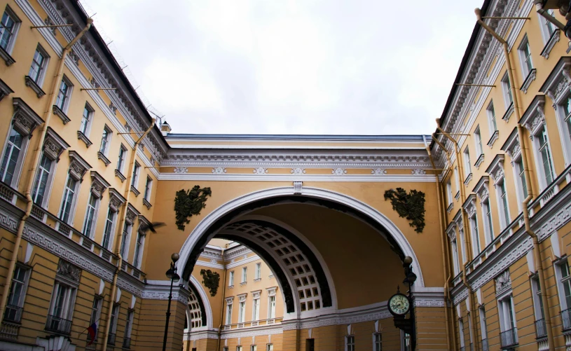 a yellow building with a clock in the middle of it, inspired by Illarion Pryanishnikov, pexels contest winner, neoclassicism, an archway, 000 — википедия, square, brown