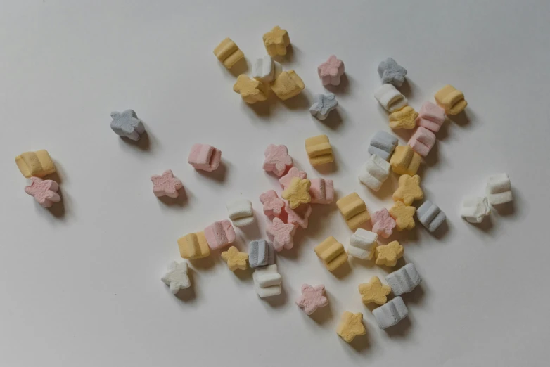 a pile of candy sitting on top of a white table, tiny stars, pastel colours overlap, milk cubes, on a gray background