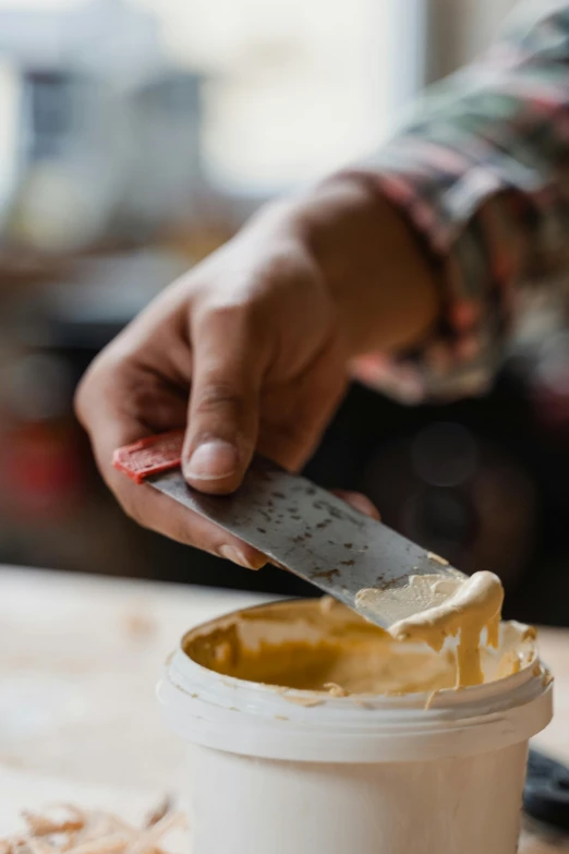 a person holding a knife over a bowl of food, by Jessie Algie, arbeitsrat für kunst, melted cheddar, in a workshop, promo image, best mayonnaise