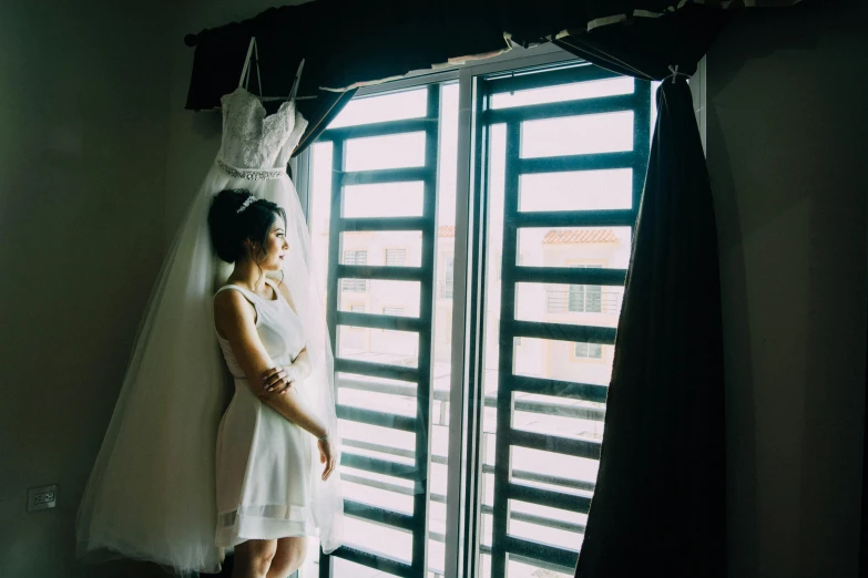 a woman in a white dress looking out a window, inspired by Elsa Bleda, unsplash, vietnamese woman, in wedding dresses, hotel room, multiple stories