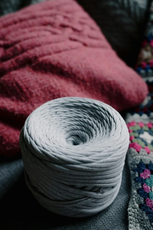 a ball of yarn sitting on top of a couch, inspired by W. Lindsay Cable, unsplash contest winner, modelling clay, flat grey color, promo image, spiral