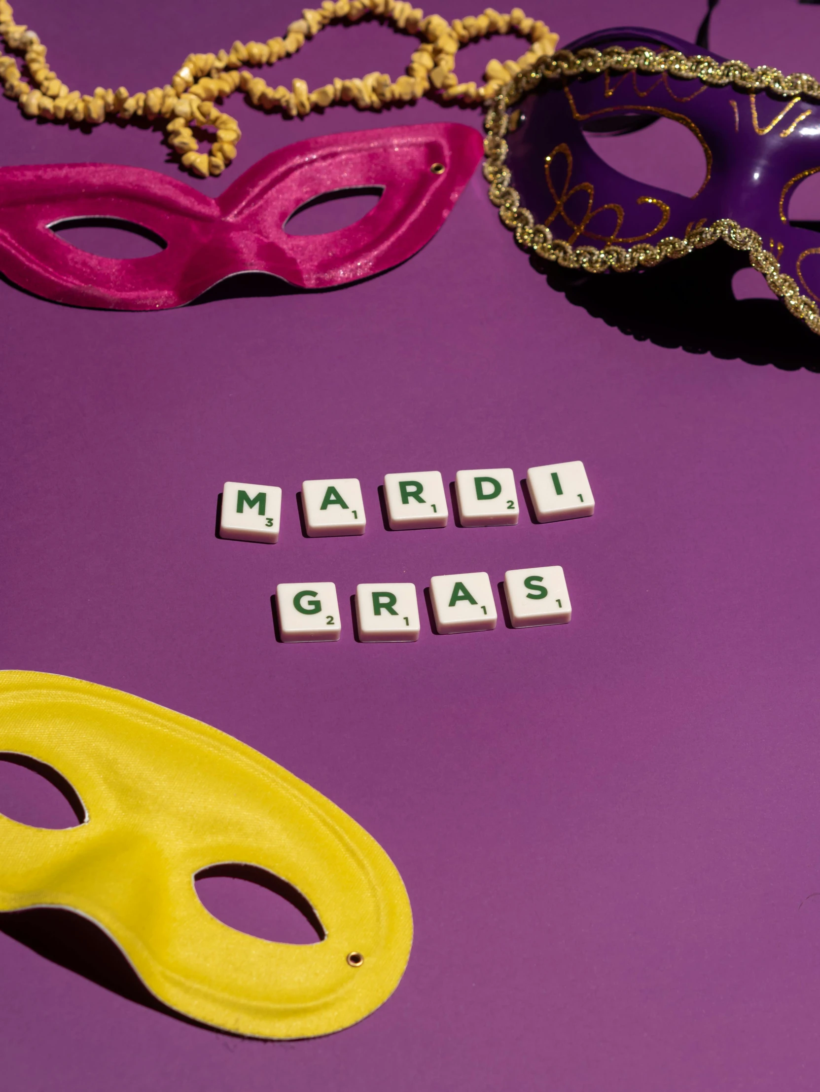 the word mardi gras spelled in scrabbles next to a pair of mardi gras masks, a photo, trending on pexels, visual art, ((purple)), may)