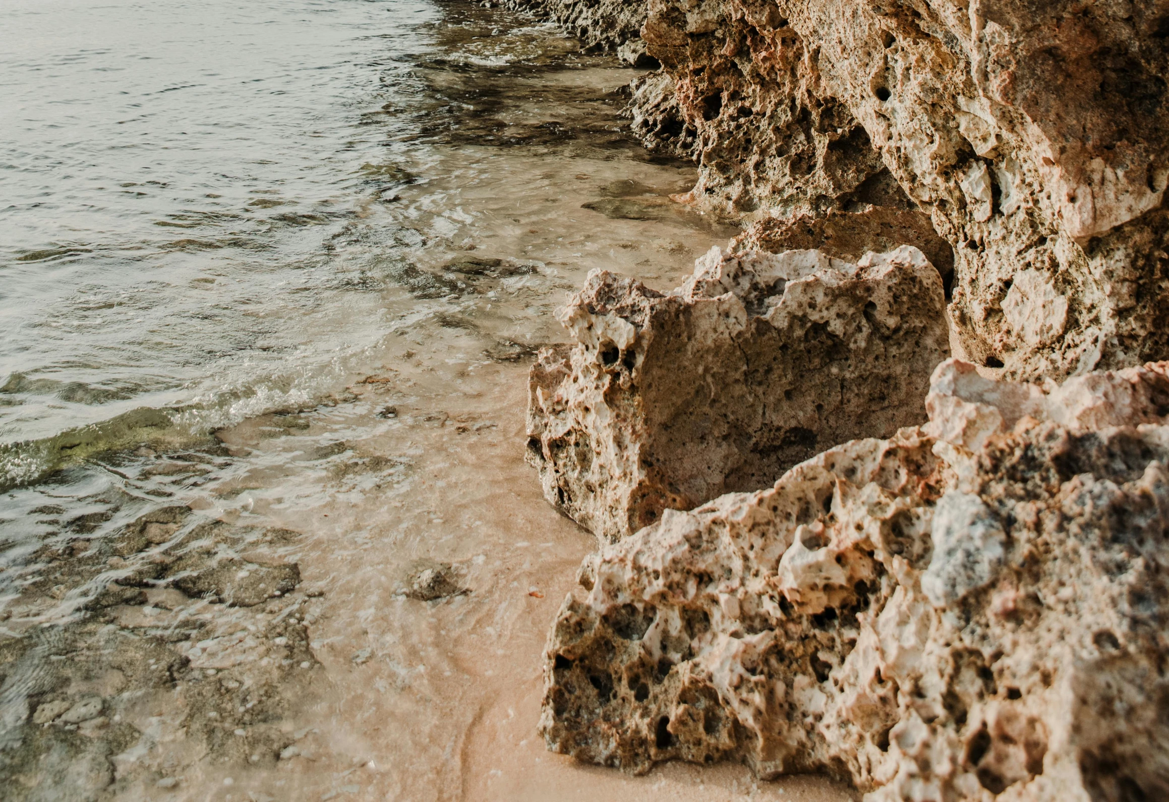 a man riding a surfboard on top of a sandy beach, an album cover, pexels contest winner, corals are gemstones, geological strata, background image, close - up photo