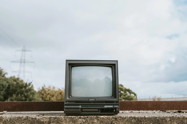 an old television sitting on top of a cement wall, unsplash, instagram post, crt tubes, looking onto the horizon, government archive photograph