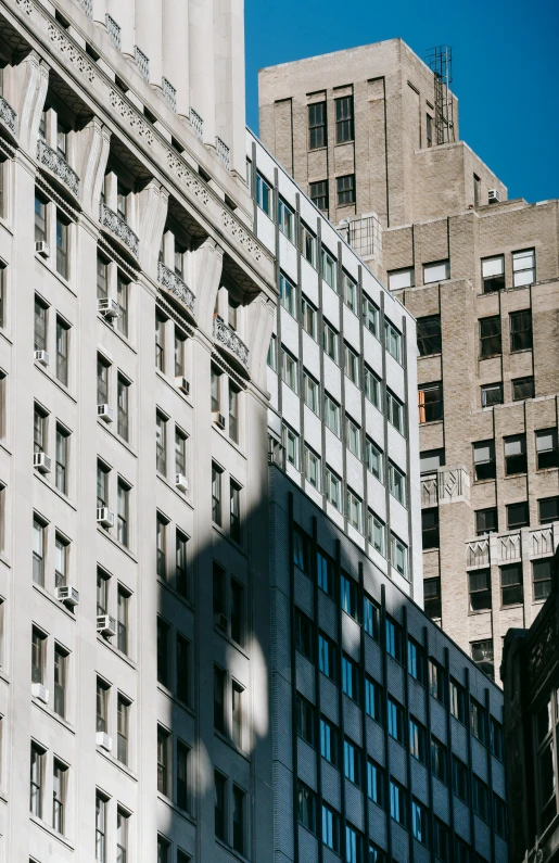 a clock that is on the side of a building, inspired by Vivian Maier, unsplash, modernism, sun and shadow over a city, new york buildings, layers of architecture, street photo