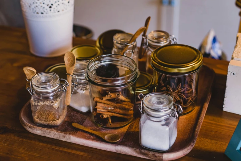 a wooden tray topped with jars filled with spices, by Daniel Lieske, pexels, fan favorite, kitchen table, vanilla, winter