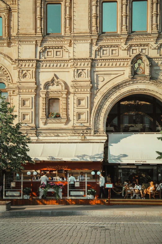 a group of people standing in front of a building, trending on unsplash, art nouveau, in moscow centre, people outside eating meals, awnings, archways made of lush greenery