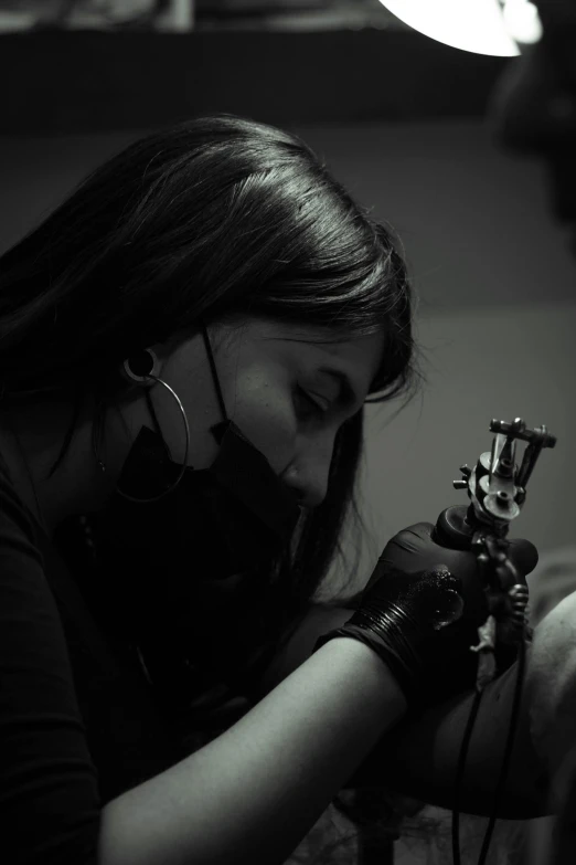 a woman getting a tattoo on a man's arm, by Alejandro Obregón, pexels contest winner, process art, in a pitch black room, photograph of a techwear woman, detailed shading, looking serious