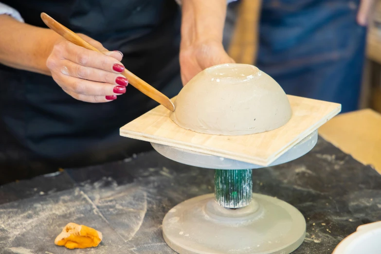 a close up of a person preparing food on a table, a marble sculpture, inspired by Hendrik Gerritsz Pot, instagram, raku, flying saucers, square, wooden bowl