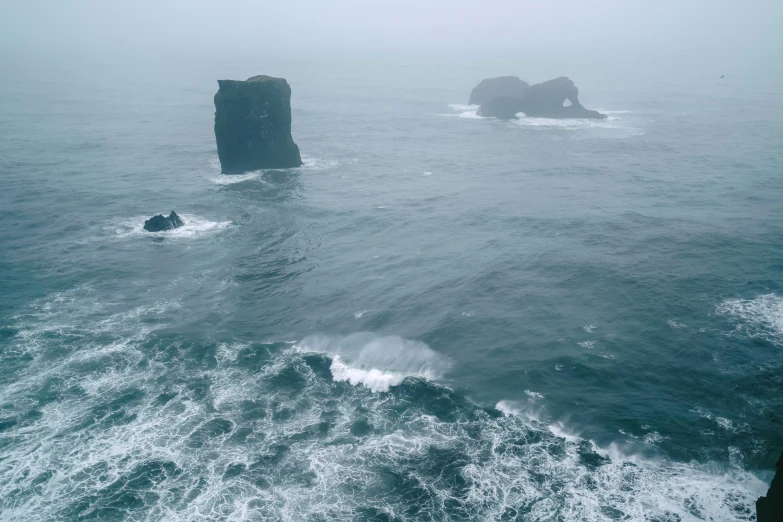 two large rocks in the ocean on a foggy day, pexels contest winner, romanticism, iceland, high res 8k, multiple stories, turbulent sea