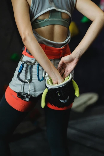 a woman standing in front of a rock climbing wall, by Adam Marczyński, pouches, thighs close up, plan, indoor shot