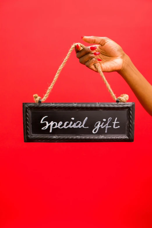 a woman holding a sign that says special gift, by Gwen Barnard, pexels, blackboard, on a red background, low detail, - 9