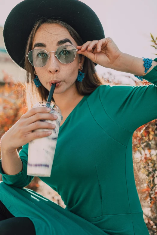 a woman in a green dress and hat drinking a milkshake, trending on pexels, wear ray - ban glass, white and teal garment, detailed product image, environmental shot