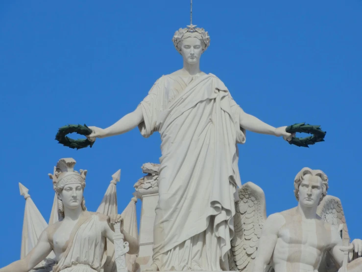 a statue of a woman holding a wreath on top of a building, some marble statues can be seen, diadems, hosada, carved white marble