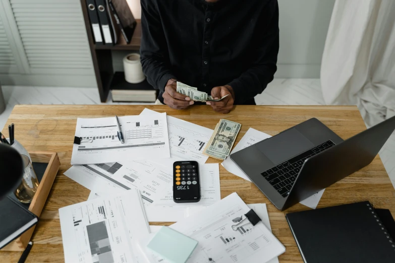 a man sitting at a table with a laptop and a calculator, pexels contest winner, hurufiyya, piles of money, a man wearing a black jacket, avatar image, man standing