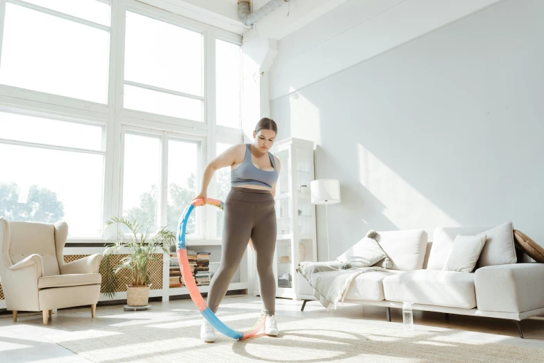 a woman playing with a hula hoop in a living room, pexels contest winner, arabesque, wearing fitness gear, low quality photo, ad image, whole body