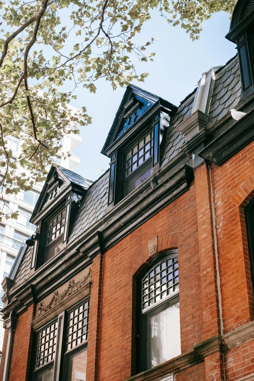 a tall brick building with a clock on the front of it, trending on unsplash, arts and crafts movement, flared japanese black tile roof, profile image, boston, gambrel roof building