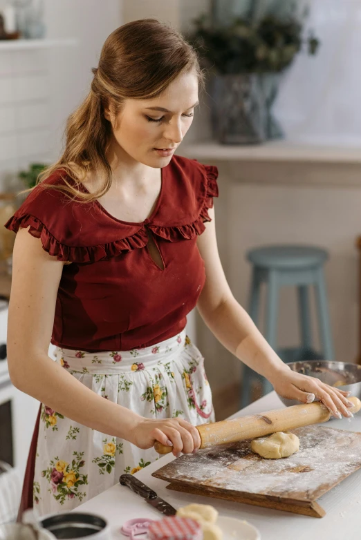 a woman rolling out dough on a cutting board, a portrait, pexels contest winner, wearing a cute top, ruffles, gif, australian