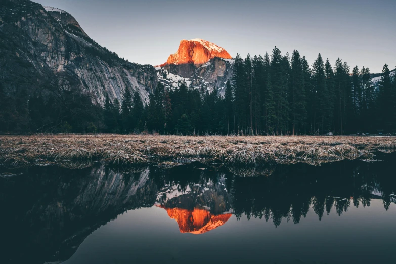 a mountain with a reflection in the water, a picture, by Marshall Arisman, unsplash contest winner, orange glow, yosemite, icy mountains in the background, mirrored