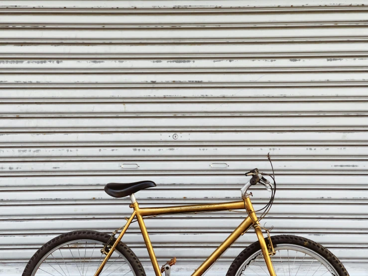 a bicycle parked in front of a garage door, unsplash, realism, gold paint, 1990's photo, metal shutter, corduroy