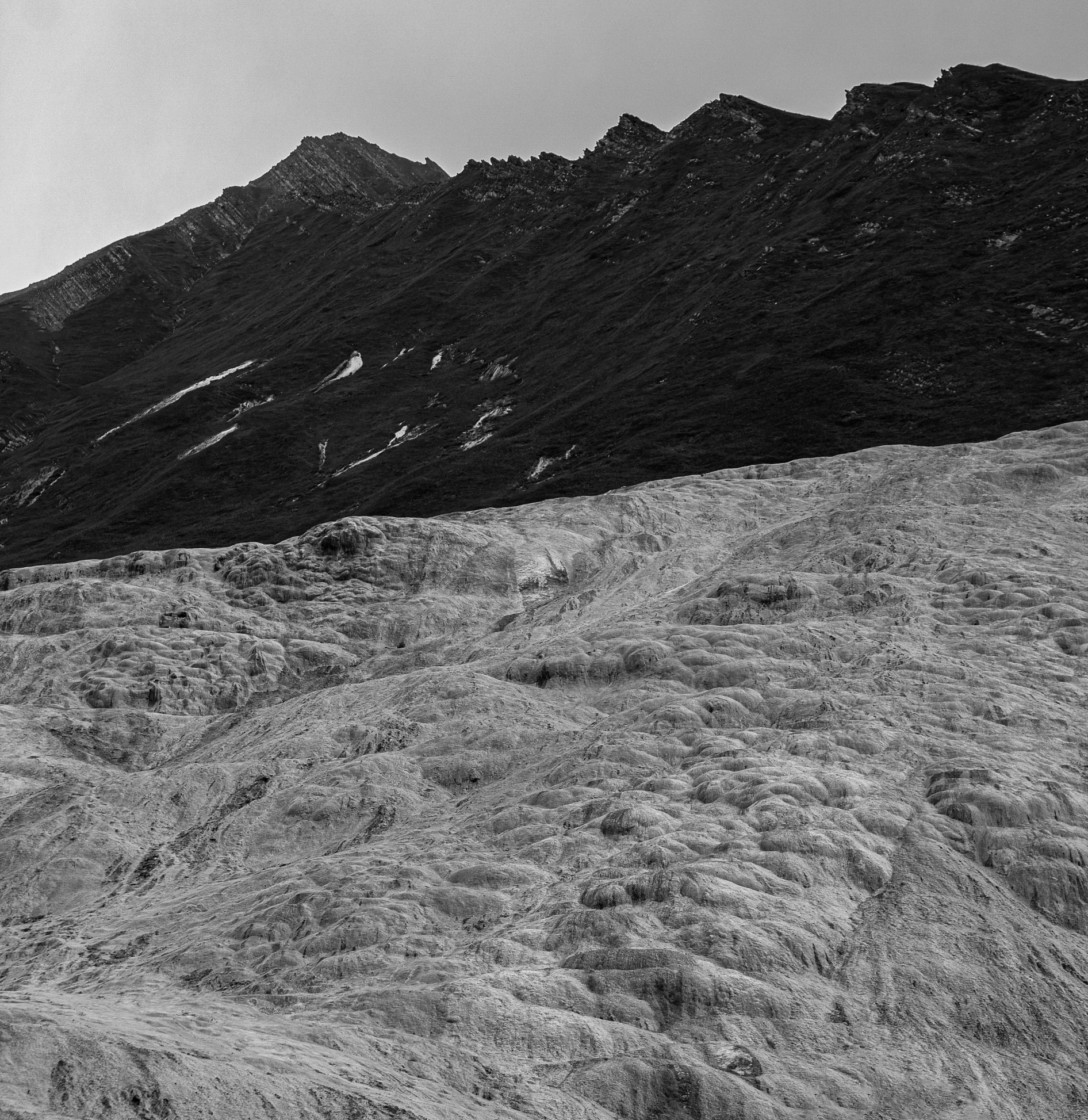 a black and white photo of a glacier, by Werner Andermatt, grass mountain landscape, jiyun chae, marble reflexes, wired landscape