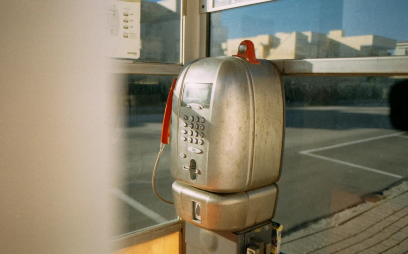 a silver pay phone sitting in front of a window, a polaroid photo, unsplash, photorealism, gas station, 2000s photo, ansel ], analogue texture