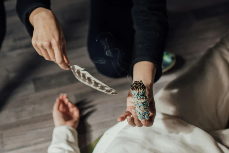 a person holding a feather in their hand, trending on pexels, smoking a bowl of hash together, lying on a mandala, crystal encrustations, tie-dye