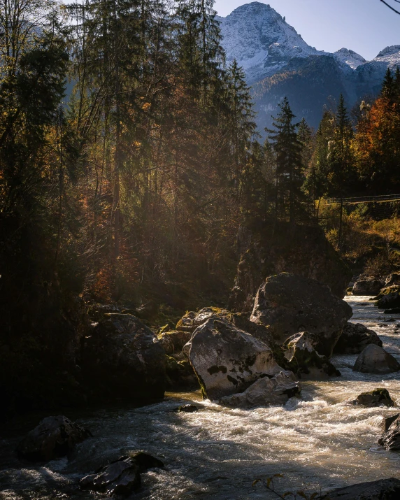 a river running through a forest next to a mountain, pexels contest winner, german romanticism, late afternoon light, autumnal, tourist photo, bursting with holy light