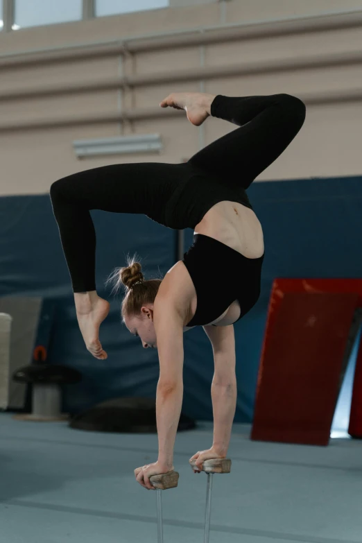 a woman doing a handstand on a balance beam, inspired by Elizabeth Polunin, arabesque, zig zag, profile image, square, low quality photo