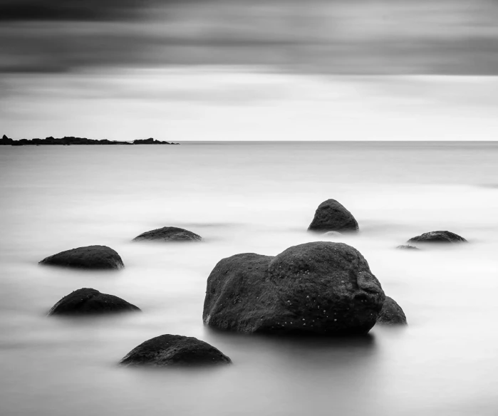 a black and white photo of rocks in the water, a black and white photo, by Daniel Gelon, serene overcast atmosphere, medium format, mind, infinity