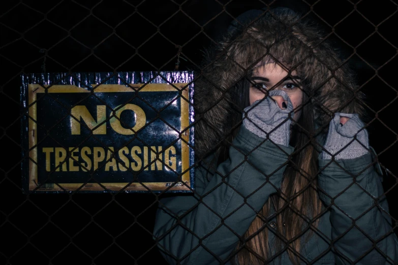 a woman covering her face behind a fence, an album cover, inspired by Elsa Bleda, trending on pexels, graffiti, coat for a rave with fur, woman holding sign, no - text no - logo, speakeasy