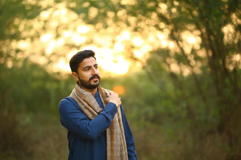 a man standing in the middle of a forest, a portrait, inspired by Manjit Bawa, pexels, visual art, wearing a scarf, elegant profile pose, warm glow, portrait image