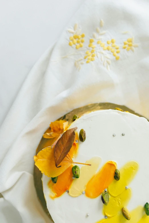 a close up of a cake on a plate, a still life, by Jessie Algie, trending on unsplash, renaissance, leaves and simple cloth, white and yellow scheme, made of silk paper, thumbnail