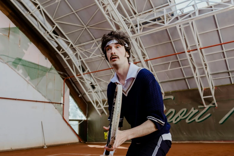 a man holding a tennis racquet on a tennis court, an album cover, by Julia Pishtar, pexels contest winner, riccardo scamarcio, in the style wes anderson, performance, indoor