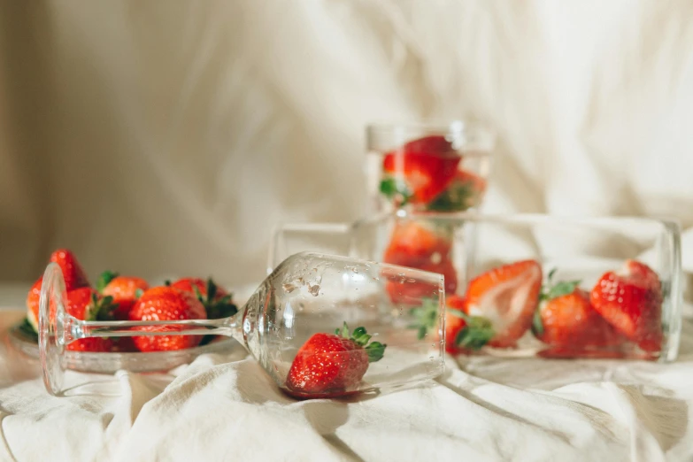 a table topped with glasses filled with strawberries, a still life, unsplash, background image, linen, low angle shot, sparkling