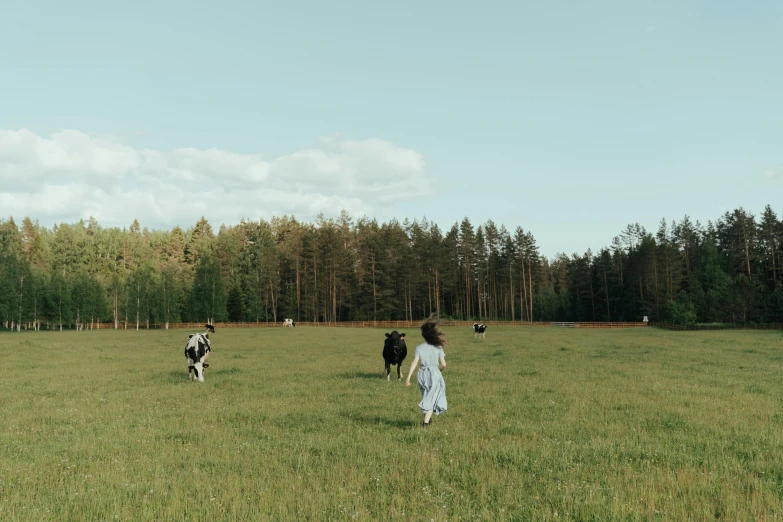 a group of people walking across a lush green field, by Emma Andijewska, pexels contest winner, surrealism, milk, forest picnic, girl running, random cows