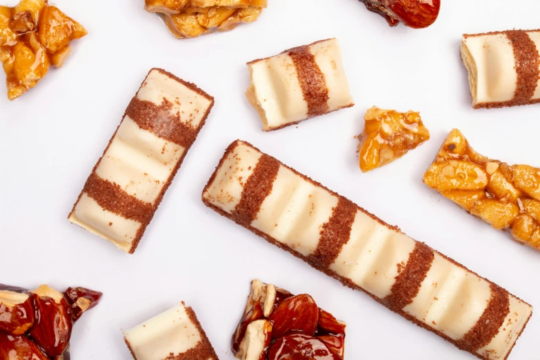 a number of pieces of food on a white surface, trending on pexels, art nouveau, eating mars bar candy, ivory, maroon, rectangular