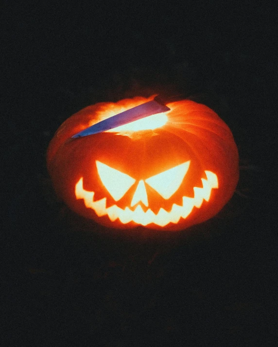 a carved pumpkin with a knife sticking out of it, by Jessie Alexandra Dick, glow sticks, lgbtq, ☁🌪🌙👩🏾, stick and poke