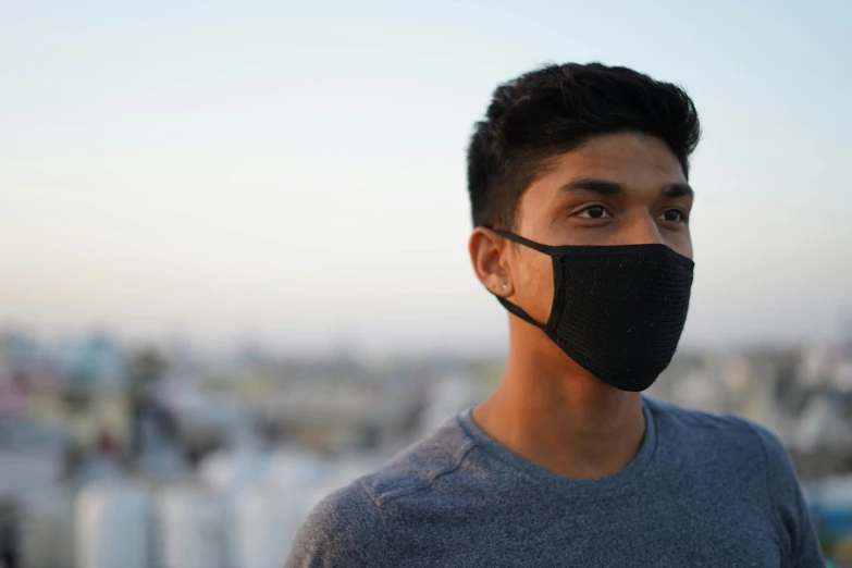 a young man wearing a black face mask, a stipple, city in background, profile image, south east asian with round face, backlit face