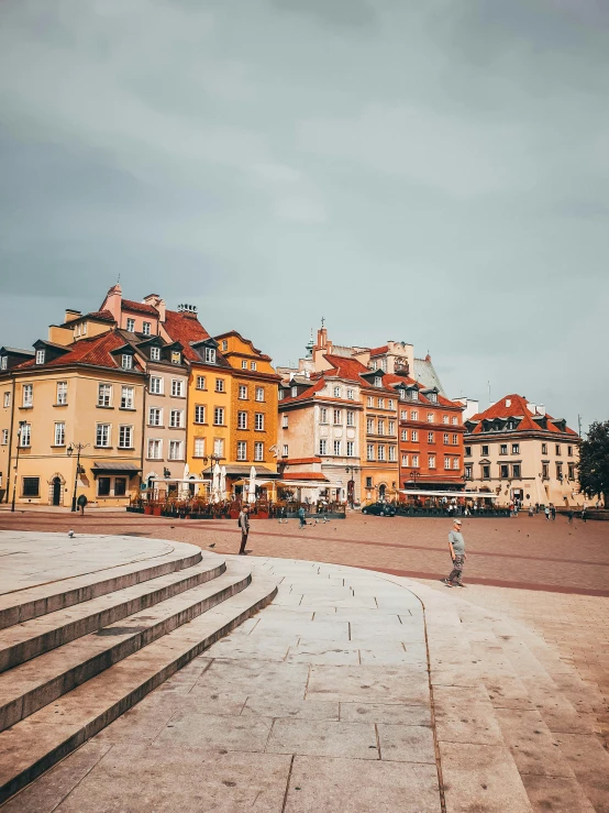 a man riding a skateboard up the side of a flight of stairs, by Emma Andijewska, unsplash contest winner, brightly colored buildings, warsaw, cathedral in the background, square