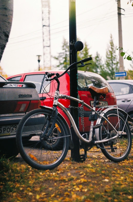 a bicycle is chained to a pole in a parking lot, by Sven Erixson, unsplash, kama russian electrocar, in fall, low quality photo, square