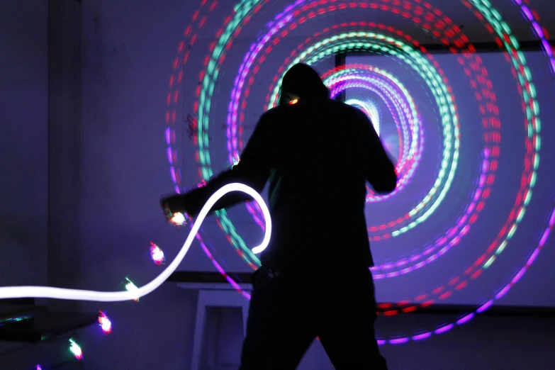 a man playing with a hula hoop in a dark room, interactive art, rave inspired, rgb wall light, outdoor rave, multi - coloured