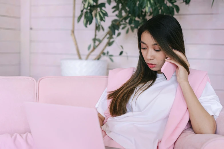 a woman sitting on a couch using a laptop, trending on pexels, wearing a pink tux, girl making a phone call, asian girl with long hair, sleepy