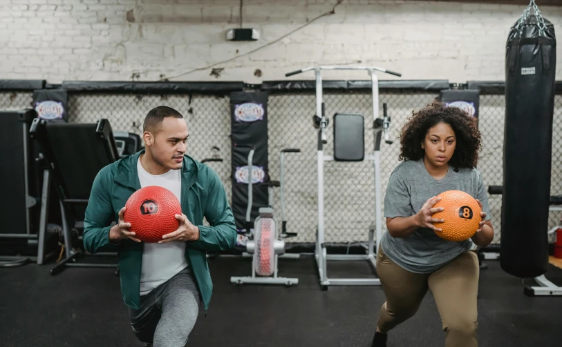 a man and a woman holding balls in a gym, by Sam Charles, pexels contest winner, thicc build, background image, working out in the field, various posed