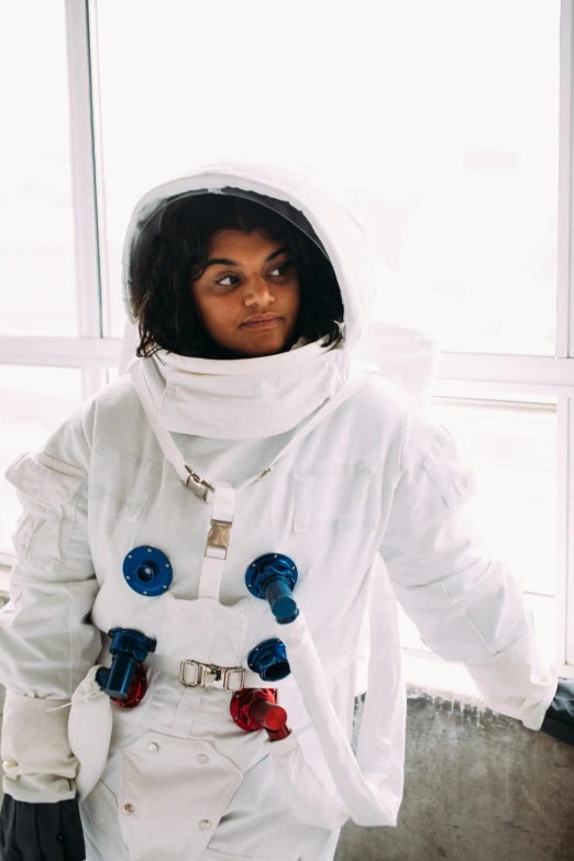 a woman in an astronaut suit standing in front of a window, black haired girl wearing hoodie, wearing white suit, riyahd cassiem, spacecrafts