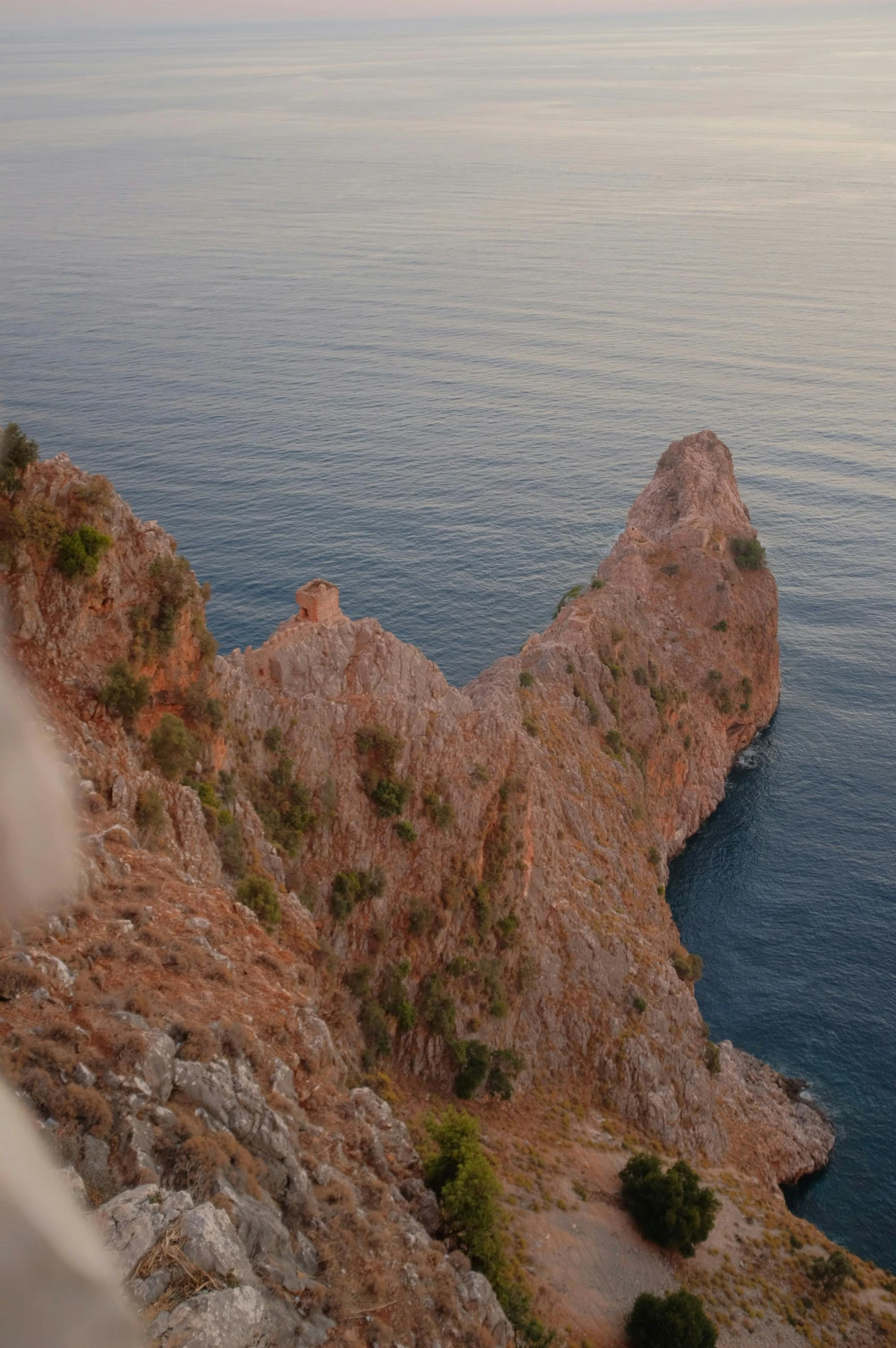 a man standing on top of a cliff next to the ocean, les nabis, close-up!!!!!, devil's horns, at dusk!, greek nose