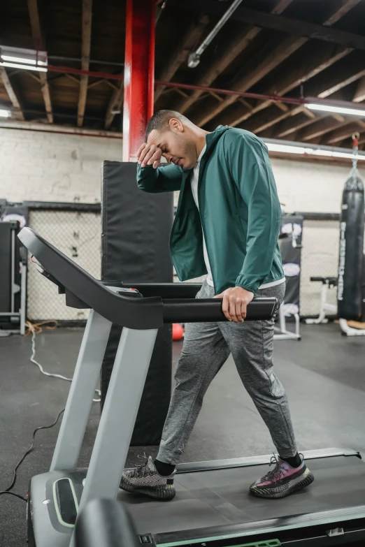 a man walking on a treadie in a gym, happening, sorrow intense likely, bending down slightly, full device, disconnection