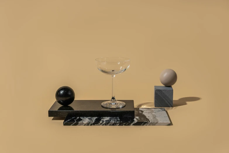 a glass of wine sitting on top of a table, a still life, inspired by Carlo Martini, kinetic art, flying black marble balls, polished white marble, charcoal and champagne, standing still